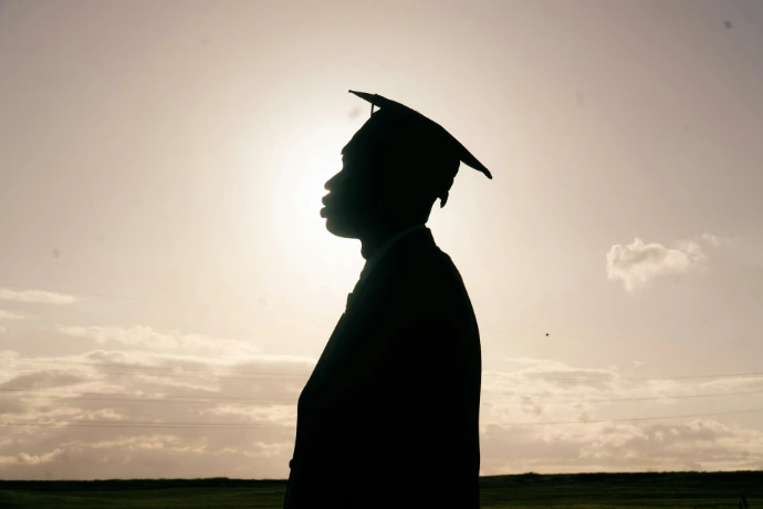 Silhouette of a graduate in a cap and gown.